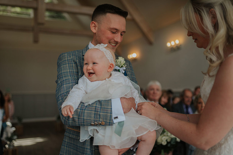 A Smiling Baby Held By A Man In A Grey Checked Suit