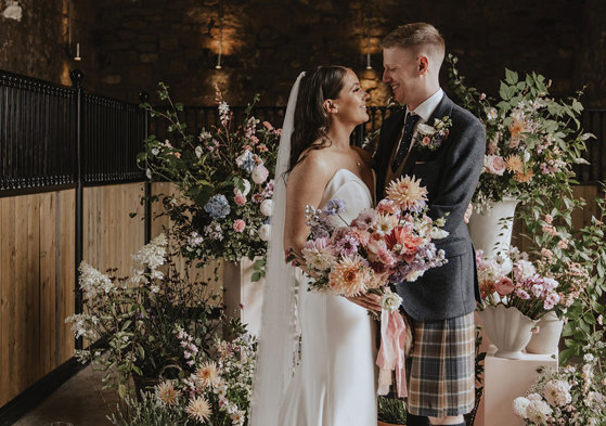 bride and groom smile with floral backdrop