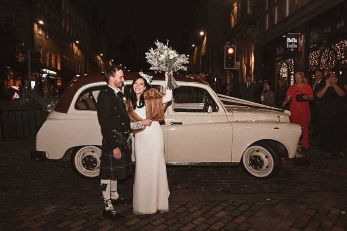 Couple pose in front of white taxi