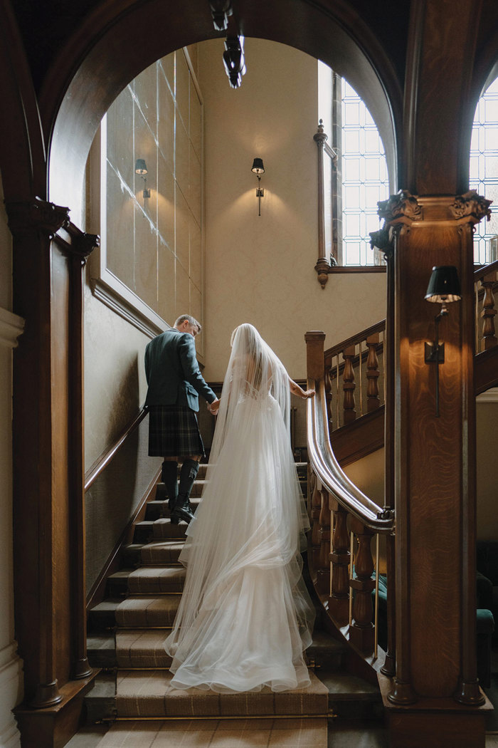 bride and groom walk upstairs holding hands inside cornhill castle 
