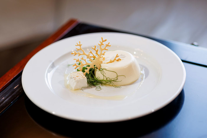 Elegant panna cotta dessert garnished with a delicate, crisp tuile and vibrant microgreens, beautifully presented on a white plate at an Old Course Hotel wedding