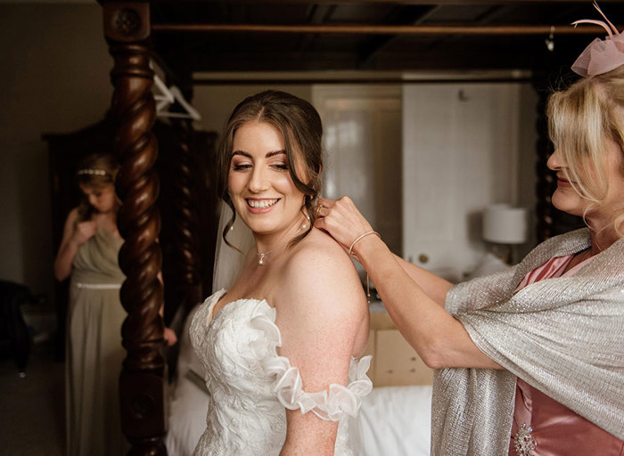 woman putting a necklace on a younger woman who is standing in front of her 