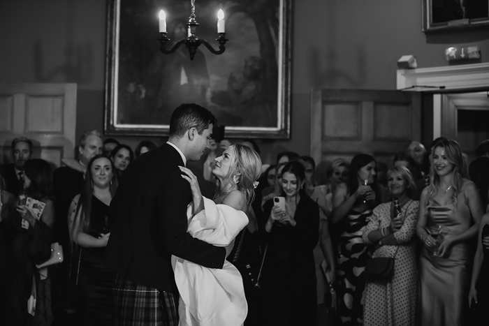 A Bride And Groom Dancing As Guests Look On