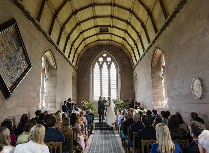 bride and groom standing at top of aisle surrounded by guests