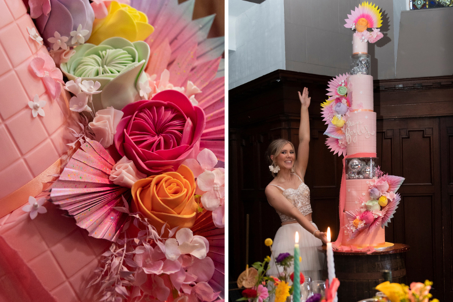 Bride poses next to colourful pink flower wedding cake with 'The Boyles' written in edible pearls made by Cake Days A Week