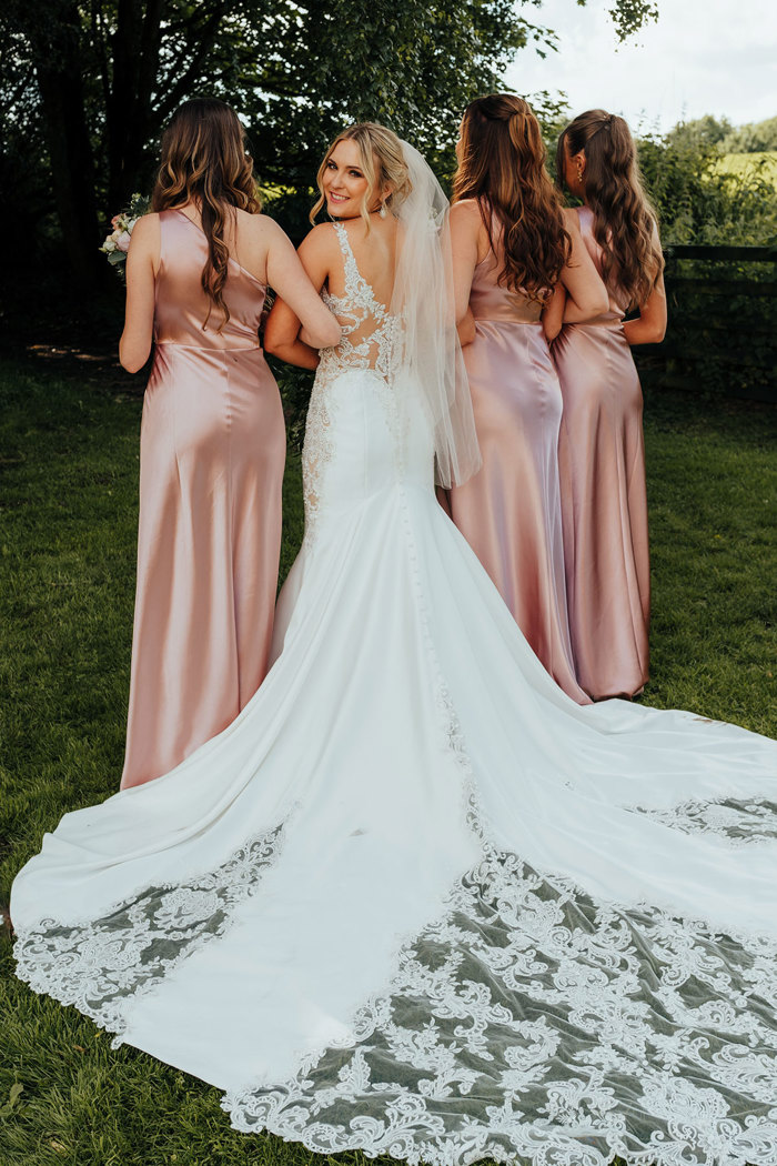 bride smiles to the camera as she shows off the back of her wedding dress