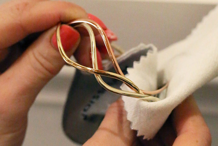 a gold bangle bracelet being hand polished with a soft cloth