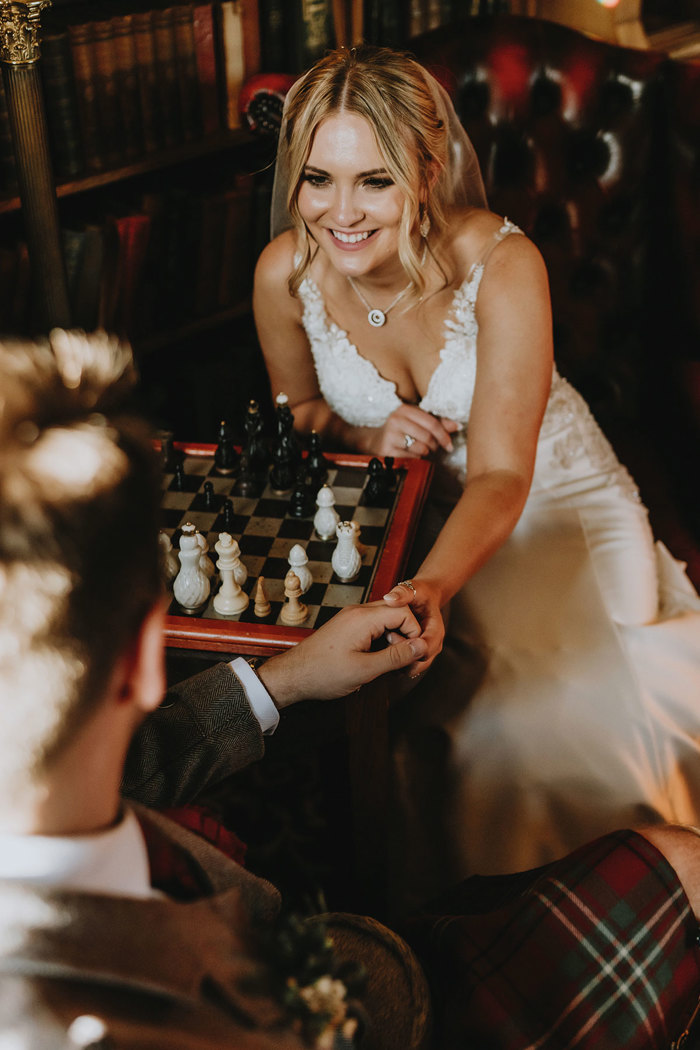 bride smiling as she plays chess on wedding day at dalhousie castle