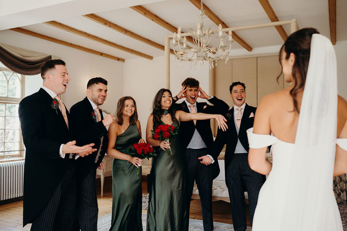 a row of people wearing formal attire looking at a bride