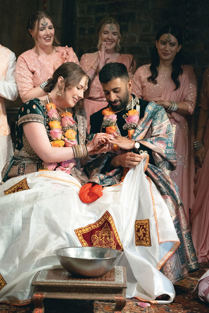 A person and person in traditional indian attire exchanging rings.