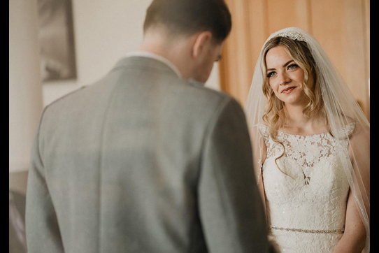 bride looking at groom lovingly at the top of the aisle 