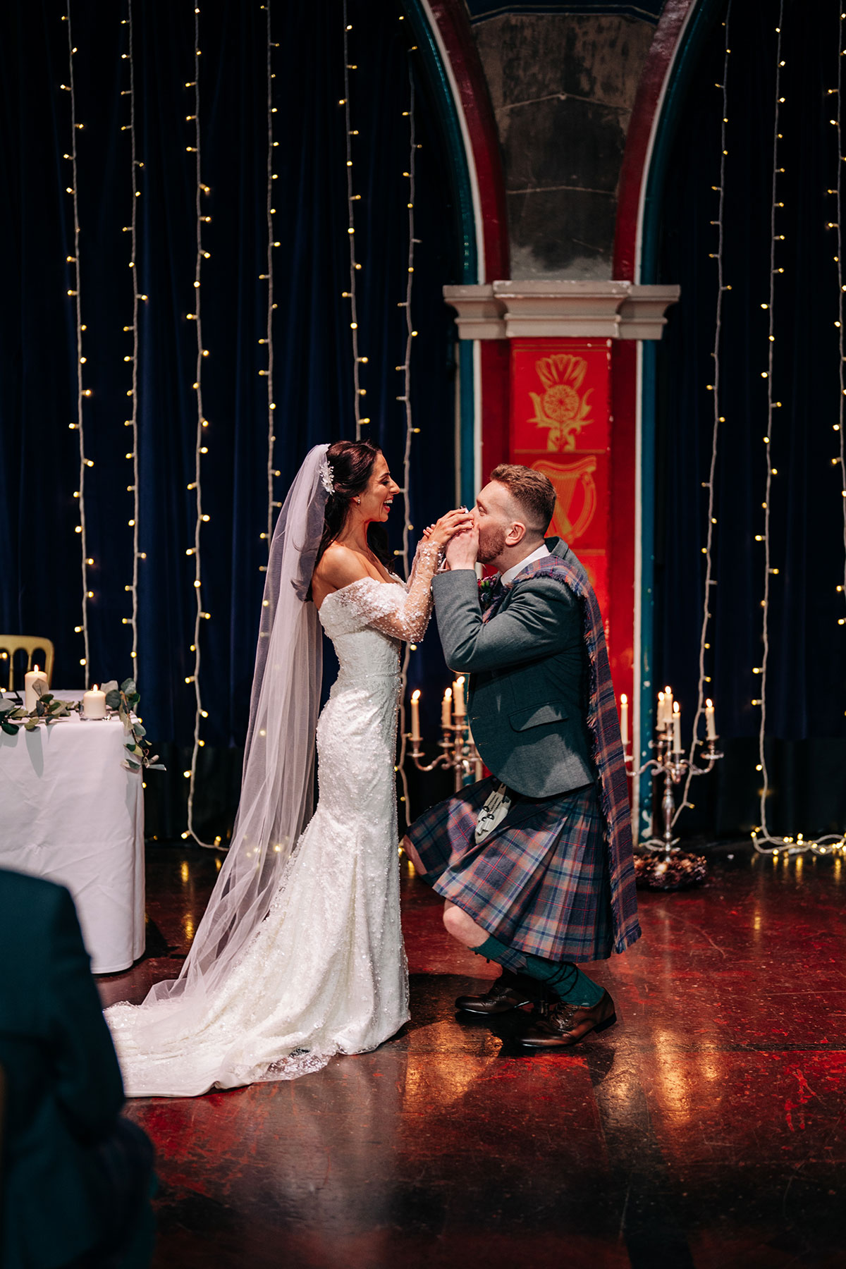 groom bends down to drink from quaich during wedding ceremony at oran mor