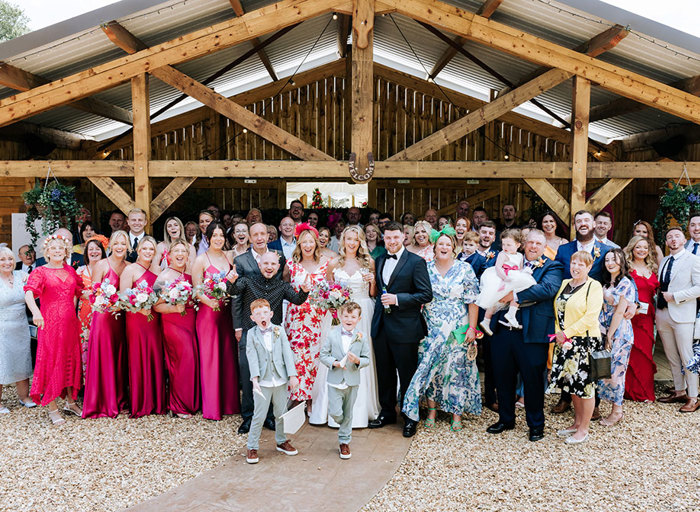 a group wedding portrait outside a wooden barn