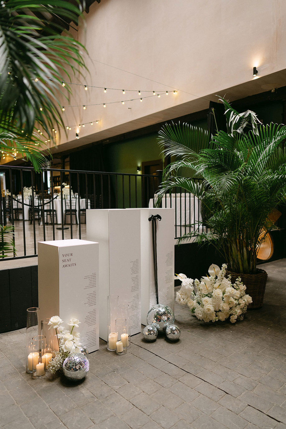 tall white box table plan with white flowers, candles and disco balls