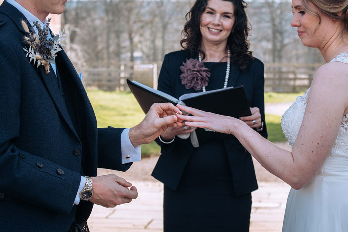 Groom puts brides wedding ring on at altar