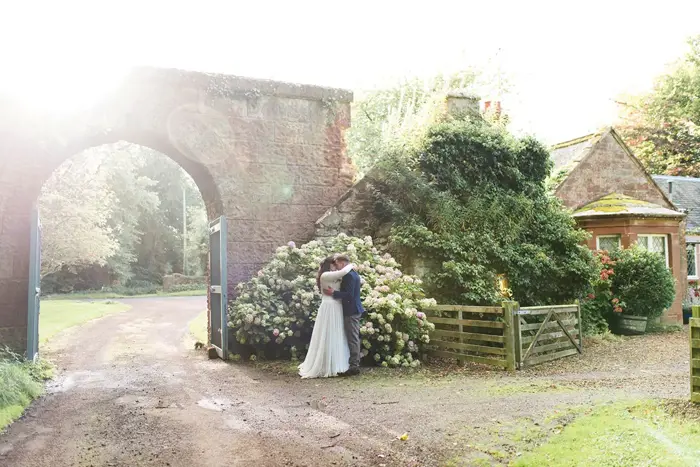 Bride and groom kiss in courtyard