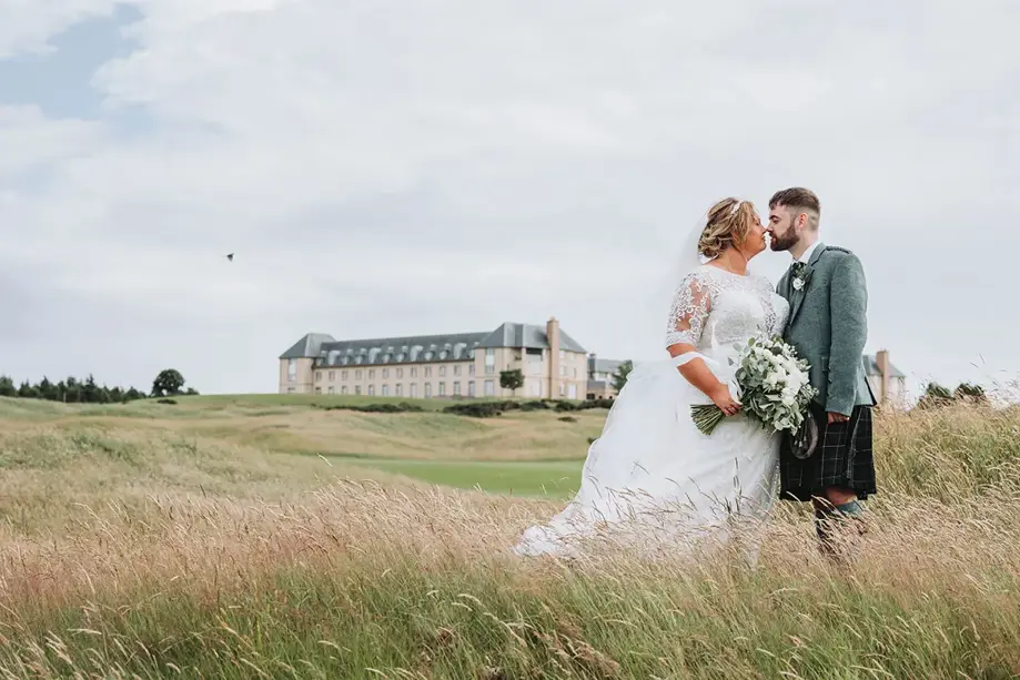 Couple in wedding outfits standing on grass