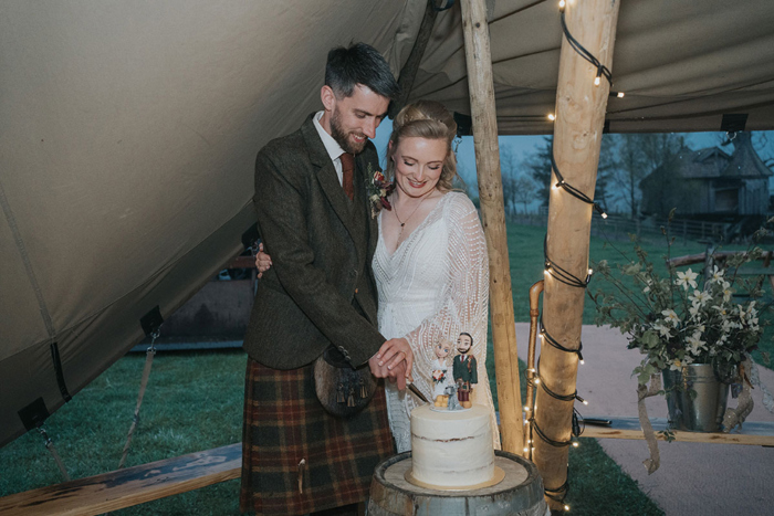 The couple smile as they cut their wedding cake