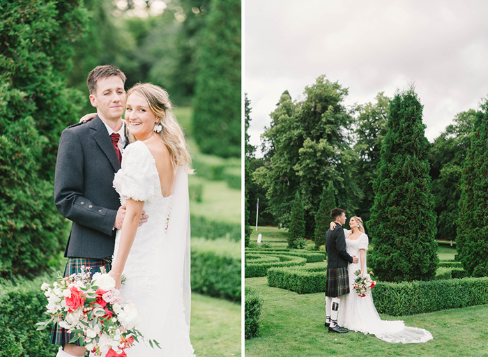 A bride and groom stand with their arms around each other in a garden