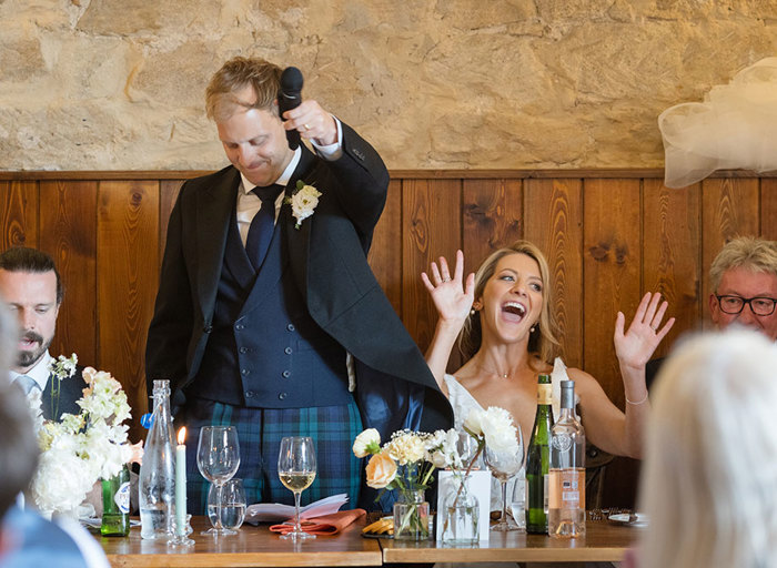 groom holding microphone and bride laughing