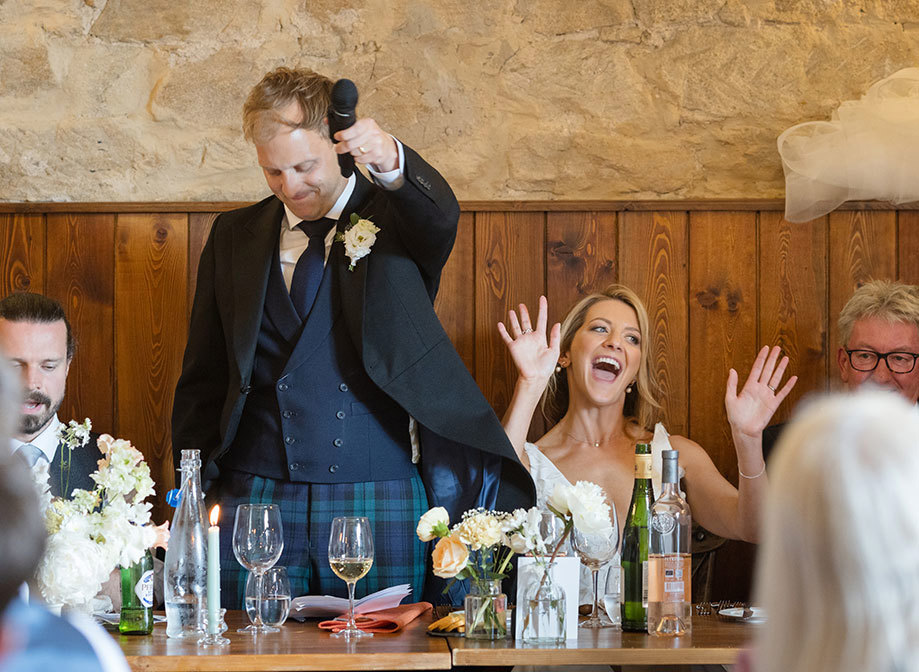 groom holding microphone and bride laughing