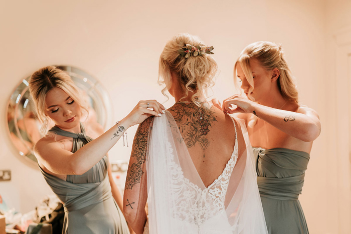 Bridesmaids fix bride's dress