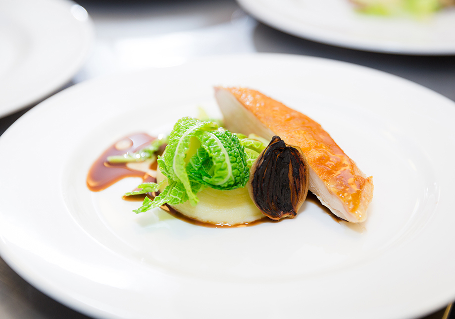 Chicken with burnt shallot, potato and cabbage on white plate