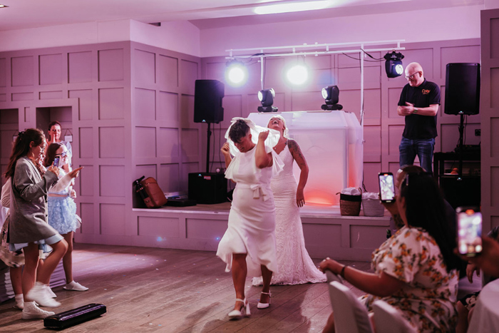 Two brides take to the dance floor wearing bridal gowns