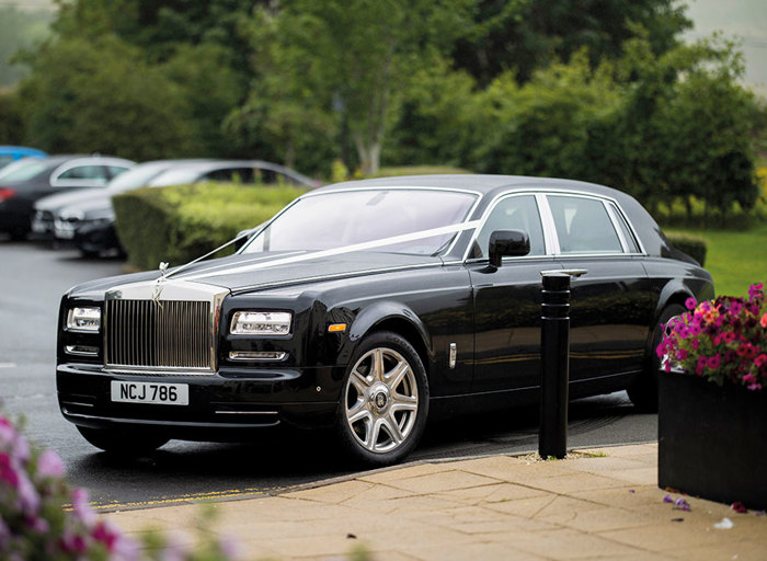 A large black saloon car with a white ribbon from the bonnet to the front doors 