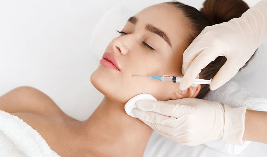 Latex gloved hands administering an injection to a person's face