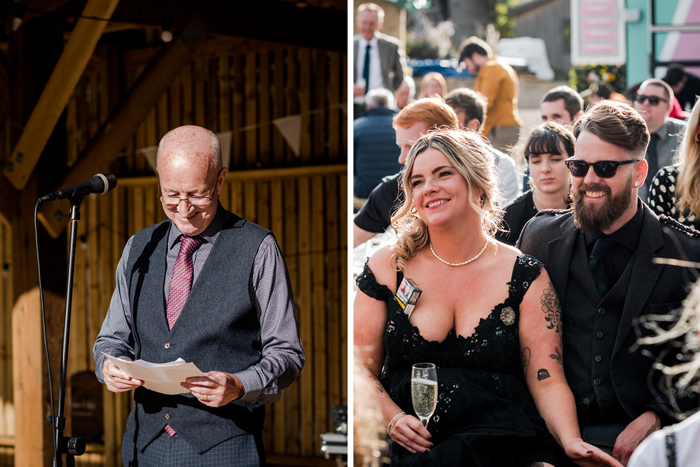 A Person Wearing A Dark Grey Waistcoat And Shirt With Dark Pink Tie Stands By A Microphone Stand While Looking Down At A Sheet Of Paper On Left And A Smiling Seated Bride And Groom Both Wearing Black On Right