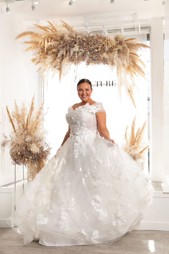 a woman wearing a wedding dress covered in floral applique.