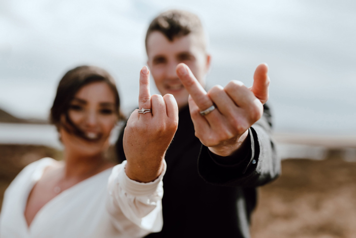 Bride and groom hold their wedding rings up for the camera