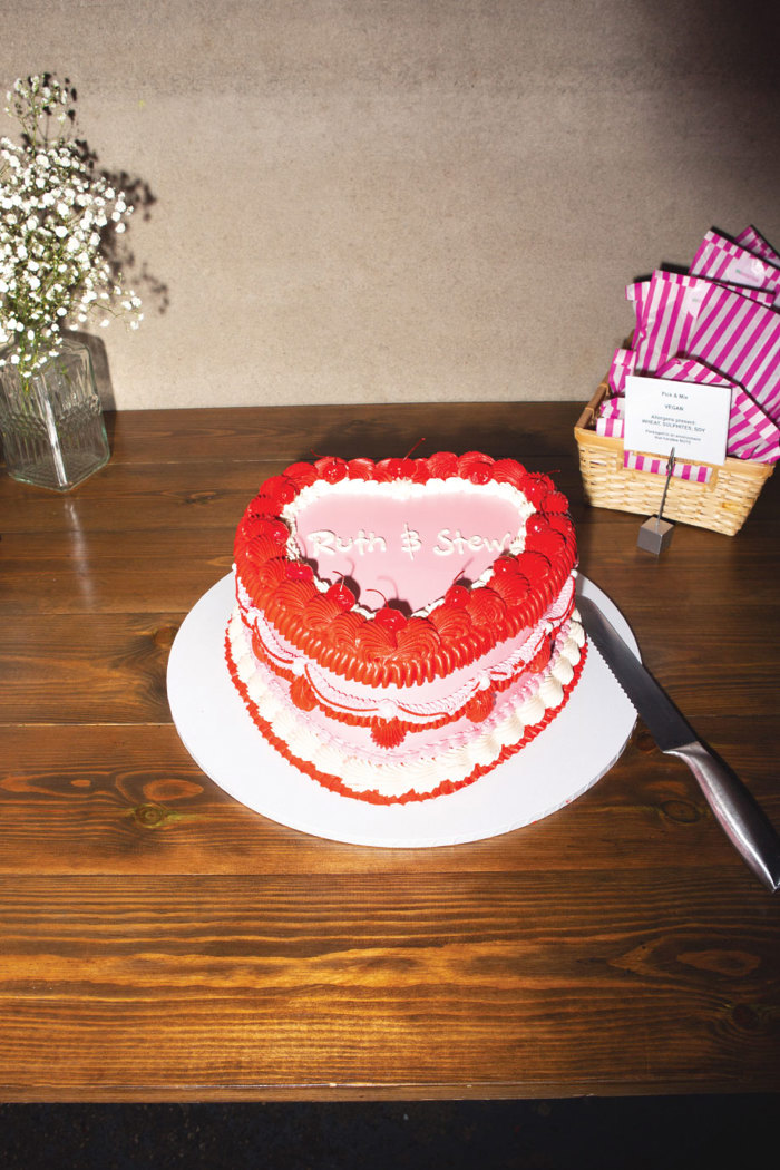 a pink and red heart retro style wedding cake on a wooden table