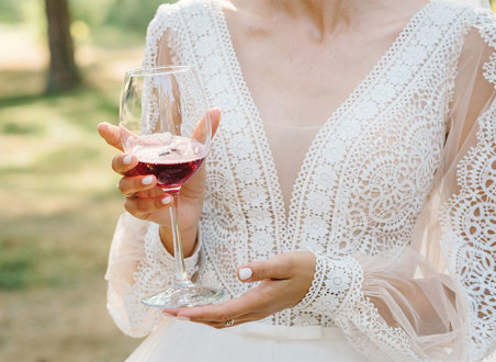 Woman wearing white lace dress holding red wine glass