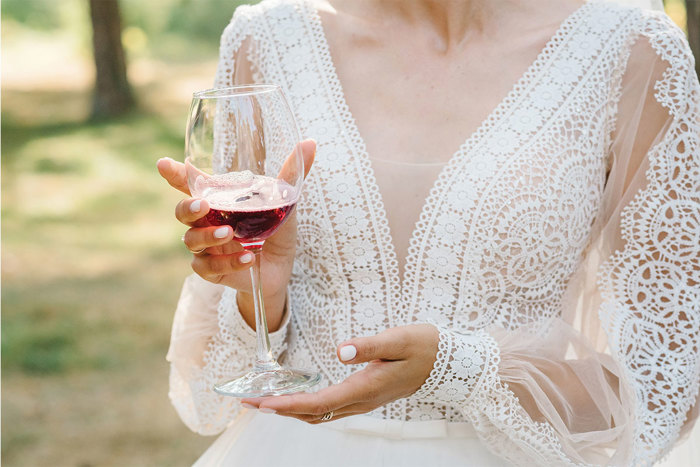 Woman wearing white lace dress holding red wine glass