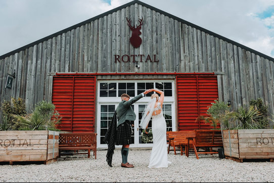 a groom twirling a bride outside the exterior of Rottal Steading