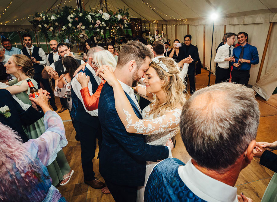 Bride and groom slow dance surrounded by other couples also dancing in the marquee