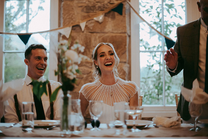 bride and groom smiling at table during wedding speeches at mar lodge