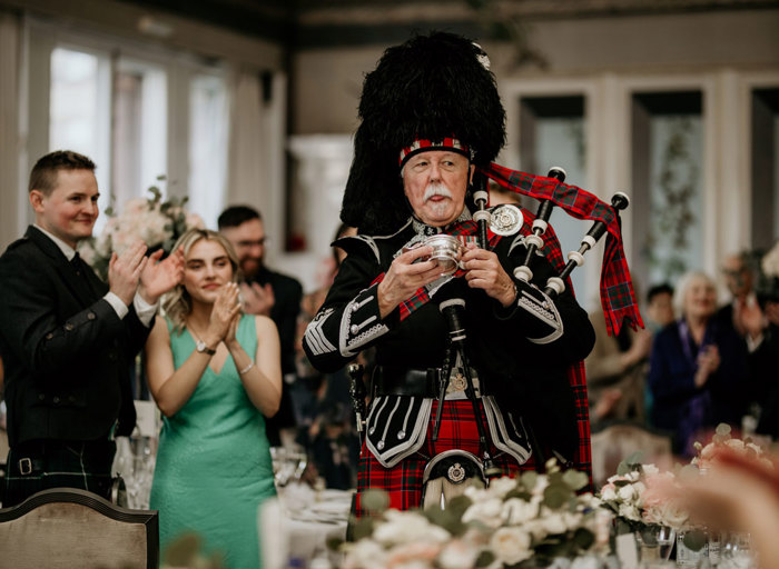 Man having a drink between his bagpipe playing