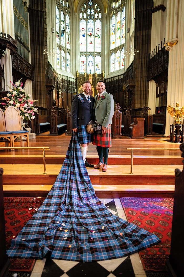 two grooms stand beside each other in church venue each wearing tartan kilts at St John’s Episcopal Church in Edinburgh