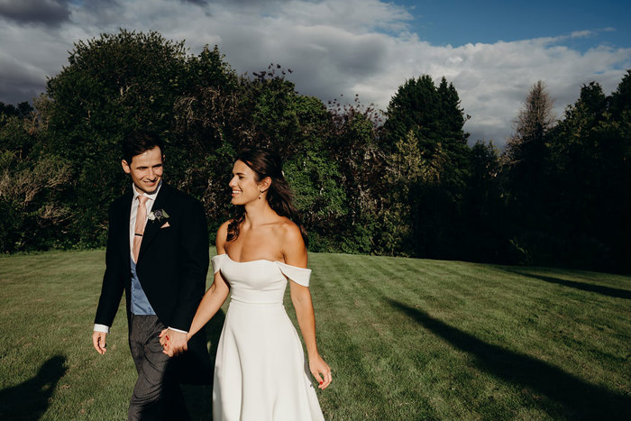 a bride and groom walking in the sunshine in a garden at Achnagairn Castle