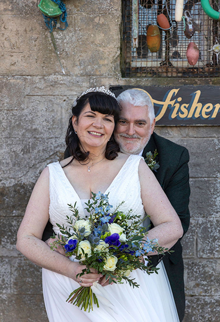 a bride and groom standing in front of a stone building that's adorned with sea paraphernalia