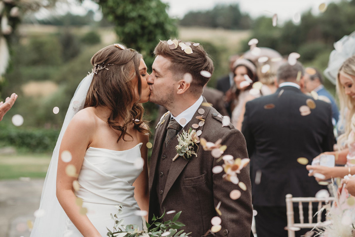 Bride and groom kiss in a confetti shower