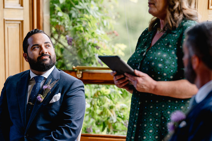 Groom looks at celebrant during wedding ceremony