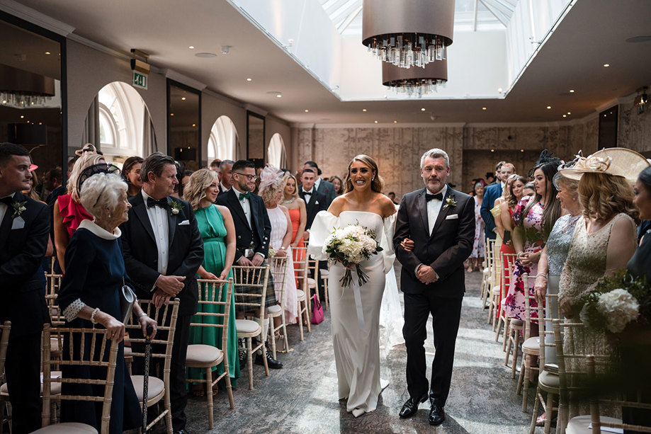 Father of the bride giving his daughter away walking down the aisle smiling