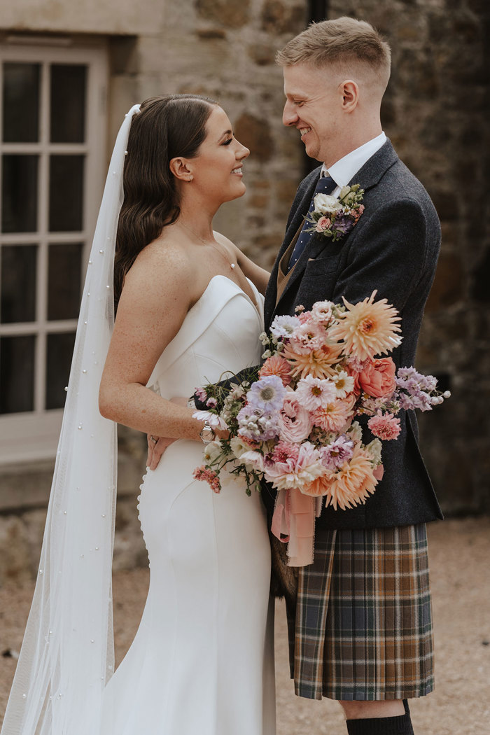 bride and groom smile at one another at falside mill