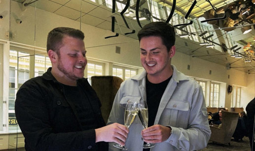 two men clinking champagne flutes in front of a mirror at ROX in Glasgow