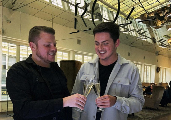 two men clinking champagne flutes in front of a mirror at ROX in Glasgow