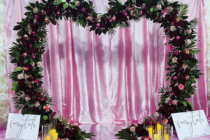 a heart-shaped flower arch and faux candles in front of a pink satin sheet